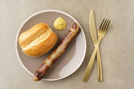 Bratwurst with bread roll and mustard on a plateの写真素材