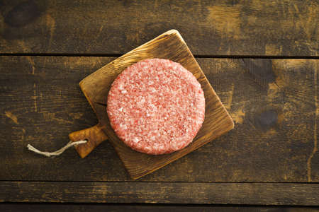 Burger patty from ground beef on wooden boardの写真素材