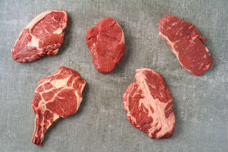 Variety of different beef steaks on grey stone