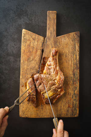 Man cutting a seared dry aged rib eye steak