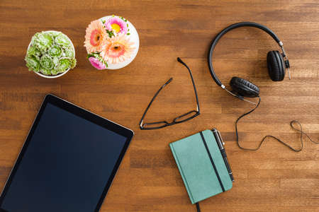 Desktop scene with tablet device, headphones and notebook shot from aboveの写真素材