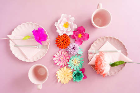 Light table decoration with paper flowers and place settings for two in pastels