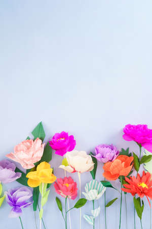 Colourful handmade paper flowers on light blue background with copyspaceの写真素材
