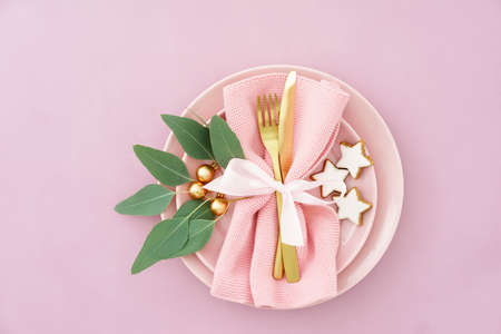 Christmas place setting in pink with golden silverware, eucalyptus and cinnamon starsの写真素材