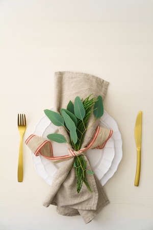 Natural Christmas place setting with golden silverware, eucalyptus and greensの写真素材