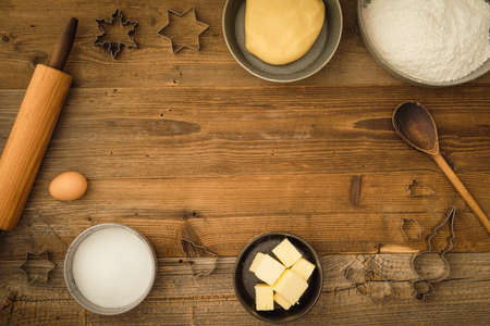 Flatlay collection of tools and ingredients for baking Christmas cookies with copyspace in the center on a dark wooden table. Shot from aboveの写真素材