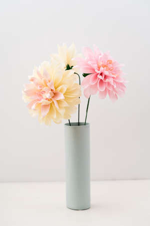 Pink and beige crepe paper dahlias in a vase on white backgroundの写真素材