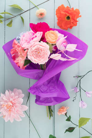 Crepe paper flower bouquet with peonies, sweet peas, poppies, ranunculus, roses and dahlia wrapped in tissue paperの写真素材