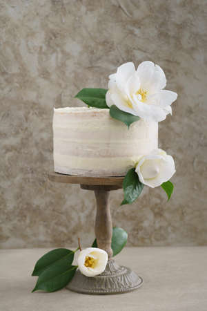 Naked buttercream layer wedding cake decorated with camellias