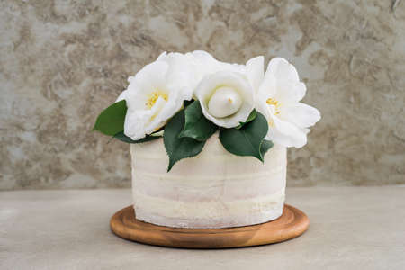 Naked buttercream layer wedding cake decorated with camellias