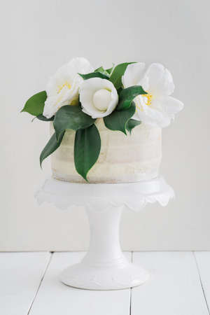 Naked buttercream layer wedding cake decorated with camellias