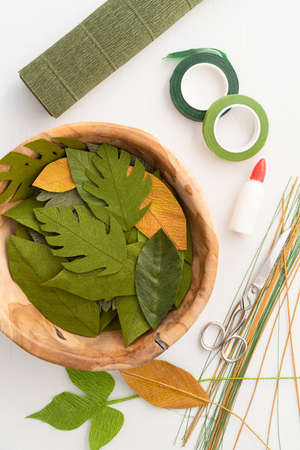Utensils for making paper flower leaves and paper flower leaves on an old wooden tableの写真素材