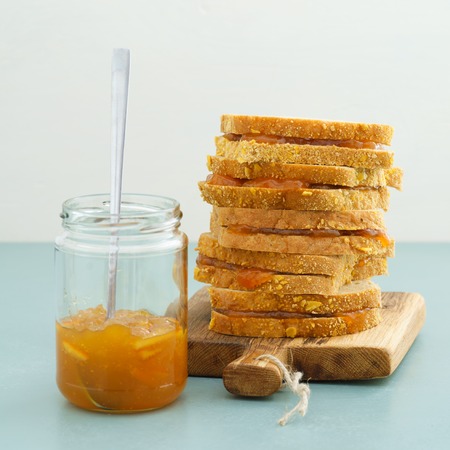 Orange jam sandwiches piled up and and marmalade jarの写真素材
