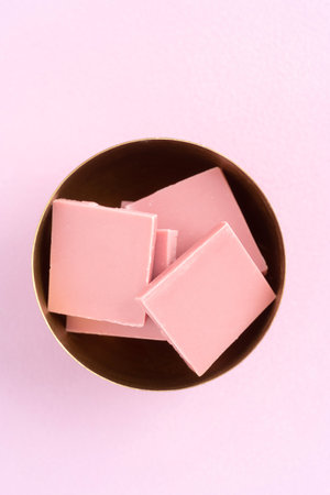 Broken pink Ruby chocolate bar pieces made from ruby cocoa beans in a bowl
