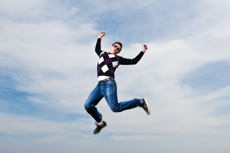 young man in the eyeglasses jumping on sky backgroundの写真素材