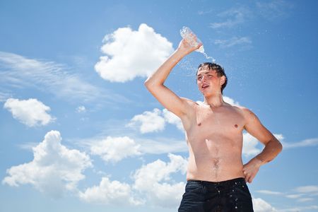 young man pour on head fresh water from bottle outdoorの写真素材