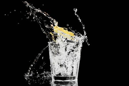 splash in a glass with lemon and ice on a black backgroundの写真素材