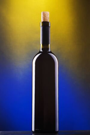 Bottle of red wine against blue and yellow backgroundの写真素材