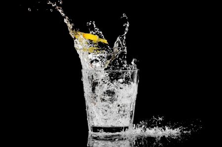 splash in a glass with lemon and ice on a black backgroundの写真素材
