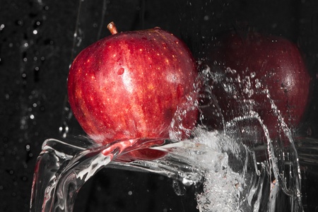 Fresh an apple in streaming splash water on black backgroundの写真素材