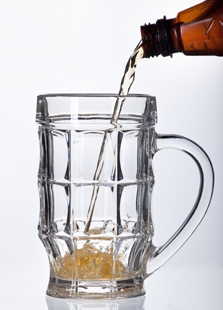 Beer pouring into beer mug isolated on whiteの写真素材