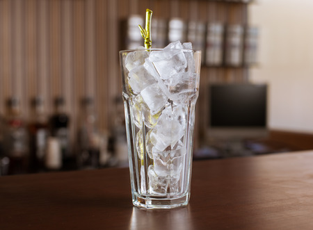 highball glass with ice and a yellow tube on the wooden barの写真素材