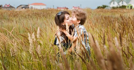young beautiful mother with son having fun on the lawn with green grassの写真素材
