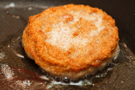 a juicy burger fresh from raw ground beef fried in hot oil closeupの写真素材