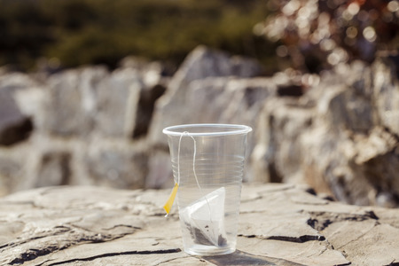 tea bag in a disposable plastic cup on a rock on the nature backgroundの写真素材