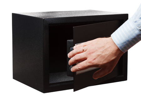 Man's hand in a striped shirt open black safe, isolated on white. Small home or hotel safe.の写真素材