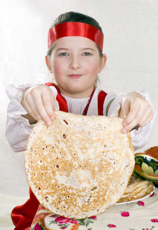 girl in Russian national clothes has control over a pancake. A Shrovetideの写真素材