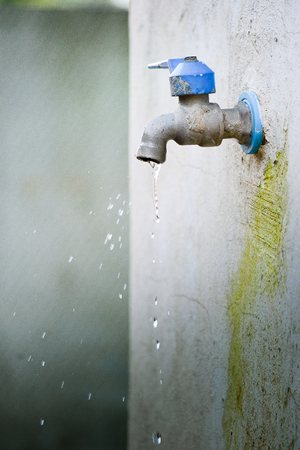 Water flow out of a tap and have moss on wall a little.background blurred.