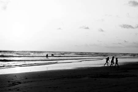 Kids playing on beach while sun is settingの写真素材
