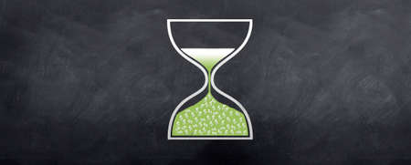 An hour glass showing dollars dropping into the lower end of the glass. Illustrating time is money.の写真素材