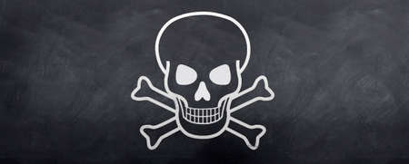 Skull and Cross bones sketched on a blackboardの写真素材