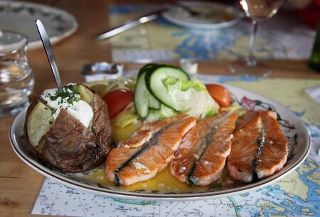 Traditional Icelandic dish with salmon steak and baked potatoes and vegetables in restaurantの写真素材
