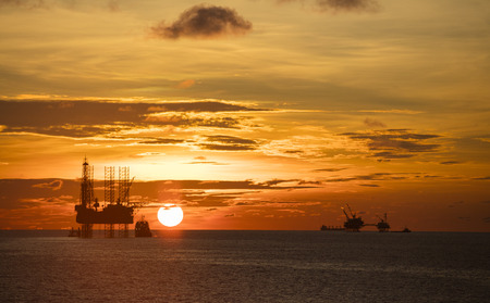 The silhouette of oil rig platform during sunsetの写真素材