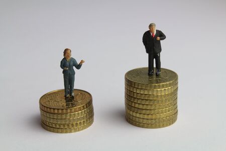A stack of coins with figures of a businesswoman and a businessman symbolize the unequal payment