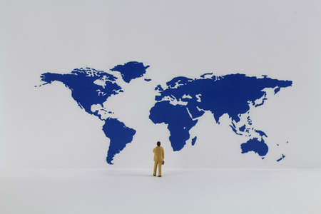 Miniature figures stand in front of a world mapの写真素材