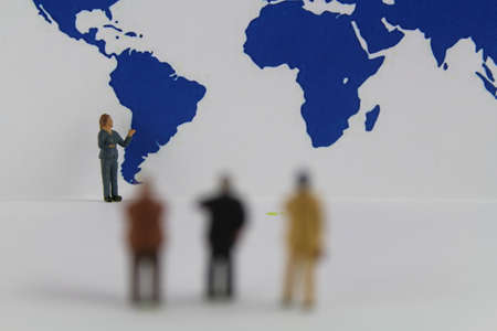 Miniature figures stand in front of a world mapの写真素材