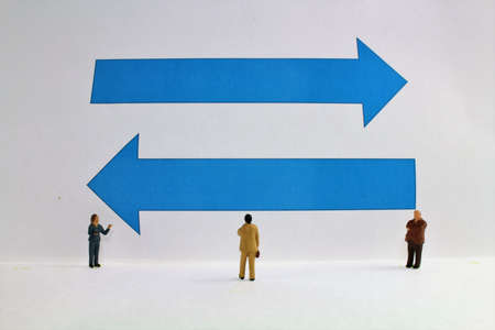 Figures of businessmen in front of blue arrows symbol for direction search and business ideasの写真素材