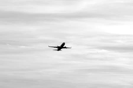 departing passenger plane with clouds in the backgroundの写真素材