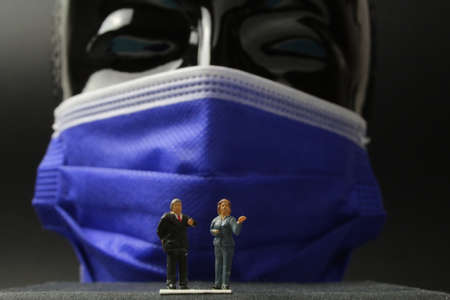 small figures in front of a large black head with protective maskの写真素材