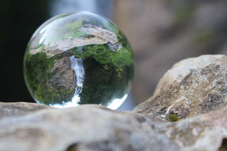 Reflective glass ball with a waterfall in the mountainsの写真素材