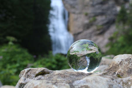 Reflective glass ball with a waterfall in the mountainsの写真素材
