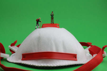 Face mask with small figures symbolizes the difficult way out of the crisis with a green backgroundの写真素材