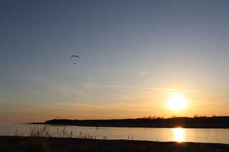 Paraglider flies in the sunsetの写真素材