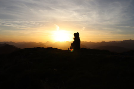 Young woman is sitting on a mountain during sunriseの写真素材