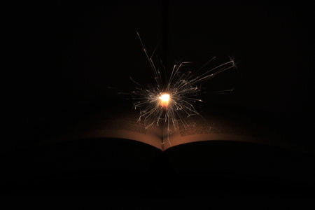 Open book with sparklers on black background, shallow depth of fieldの写真素材