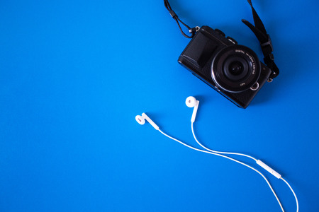 top view with digital camera and headphones White placed on a blue background,Holiday Adventure Travel Lifestyle Concep,Flat lay design creative space for journeyの写真素材